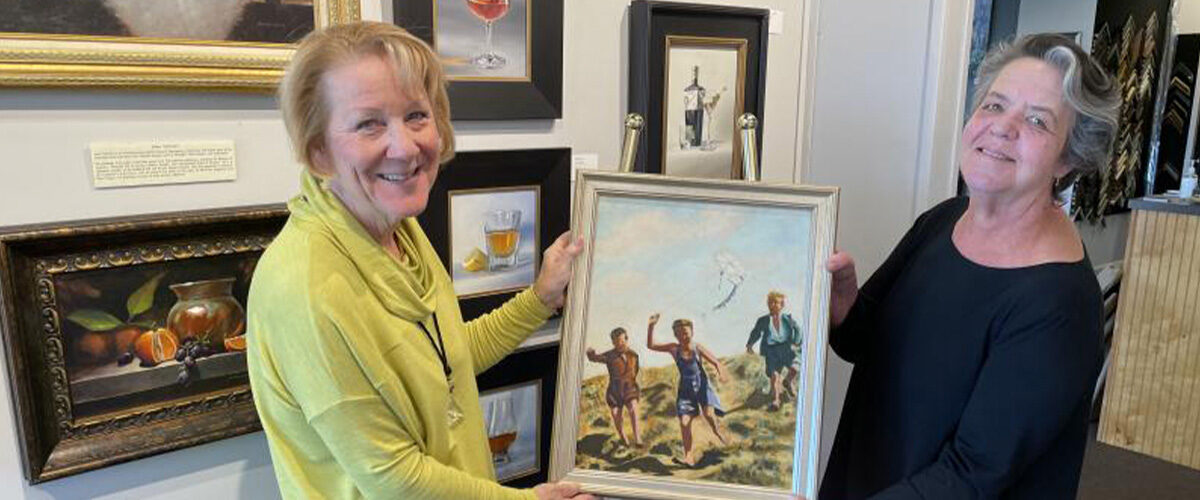 Carol Boyd-Heron, right, helped Lisa Graff choose the perfect frame for her late father’s painting titled “Boys and a Kite” after it was restored.